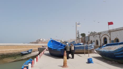 Blaue-Fischerboote-Warten-Im-Hafen-Auf-Reparaturen