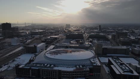 Little-Caesars-Basketball-Arena-Y-El-Centro-De-Detroit-Con-Nubes-De-Tormenta-Arriba,-Vista-Aérea