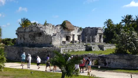Tourists-visiting-the-House-of-the-Columns-at-Tulum-archeological-site,-Quintana-Roo,-Mexico