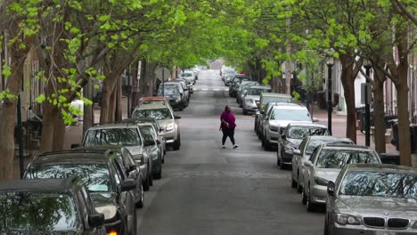 Mujer-Saliendo-Del-Coche-En-Una-Larga-Calle-De-Sentido-único-Cubierta-Con-Un-Dosel-De-árboles-Verdes-En-Primavera