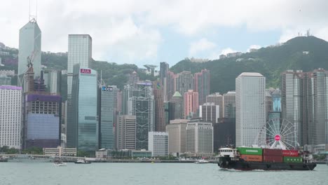 A-cargo-ship-carrying-containers-sails-across-the-Victoria-Harbour-waterfront-in-front-of-the-Hong-Kong-skyline