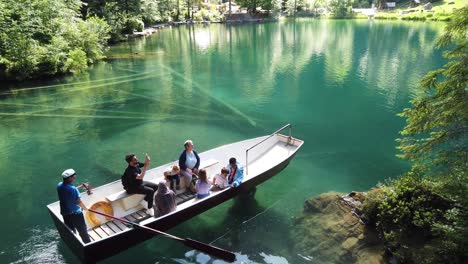 Familias-De-Turistas-Multiétnicos-Disfrutando-De-Un-Paseo-En-Bote-Con-Fondo-De-Cristal-En-Aguas-Cristalinas-De-Color-Turquesa-Del-Famoso-Lago-Alpino-Blausee-En-Kandersteg,-Suiza