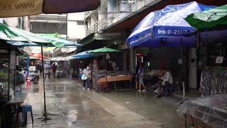 Menschen-Und-Lokale-Händler-Warten-Darauf,-Dass-Der-Regen-In-Silom-Soi-10,-Bangkok,-Thailand-Aufhört
