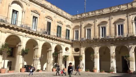 Innenhof-Des-Palazzo-Dei-Celestini-In-Lecce-Mit-Touristen,-Die-In-Zeitlupe-Laufen