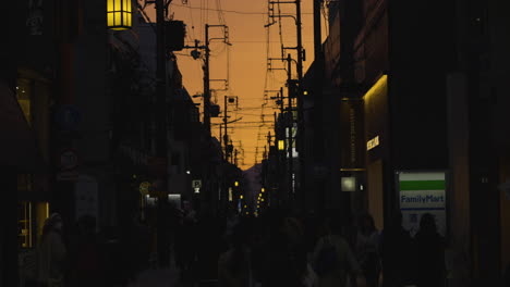 Zeitlupenaufnahme-Von-Silhouetten,-Die-Während-Des-Sonnenuntergangs-In-Kyoto-Entlang-Einer-Straßenbahnschiene-Laufen