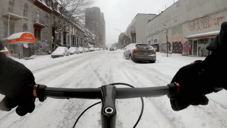 Vista-Del-Manillar-POV-En-Bicicleta-Por-Una-Carretera-Cubierta-De-Nieve-En-El-Barrio-Del-Centro-De-Montreal