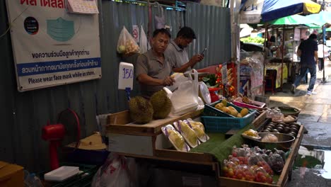 Los-Vendedores-De-Frutas-Empacan-Frutas-Mientras-Esperan-A-Los-Clientes-En-El-Mercado-Local-En-Silom-Soi-10,-Bangkok,-Tailandia