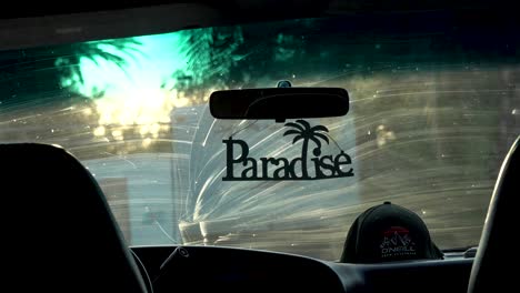 Paradise-letters-decoration-hanging-from-rear-view-mirror-in-van-with-O'Neill-branded-cap-in-dashboard,-Inside-shot