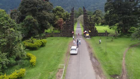 Aerial,-tourists-standing-in-line,-girl-posing-for-a-photo-at-Handara-Resort-Gate,-famous-Iconic-Tourist-Attraction-in-Bali-Indonesia