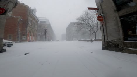 POV-Por-Una-Calle-Lateral-Y-Hacia-La-Carretera-Principal-Durante-Una-Tormenta-De-Nieve-En-El-Centro-De-Montreal