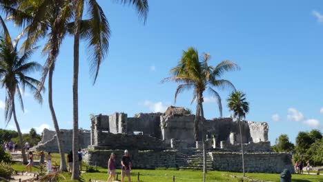 Tourists-visiting-The-Palace-at-Tulum-archeological-site,-Quintana-Roo,-Mexico