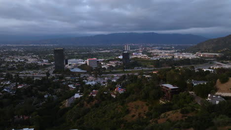 Aerial-view-away-from-the-Universal-City,-revealing-people-at-the-viewpoint,-evening-in-LA,-USA---reverse,-drone-shot