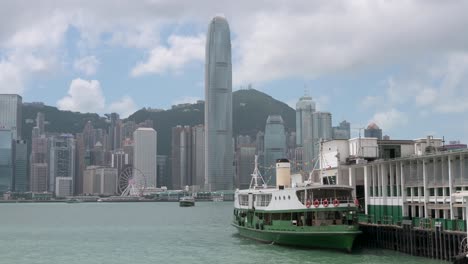 Eine-Star-Ferry-Legte-An-Einem-Fährterminal-Am-Wasser-Im-Victoria-Harbour-In-Hongkong-An,-Während-Im-Hintergrund-Die-Skyline-Von-Hongkong-Zu-Sehen-Ist