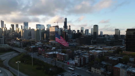 Aerial-view-approaching-a-US-Flag-in-Chicago-city,-beautiful-morning-in-Illinois,-USA