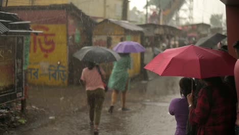 People-stuck-in-rain-with-umbrellas-open-looking-outside,-monsoon-season,-slow-motion-shot-of-rain-drops