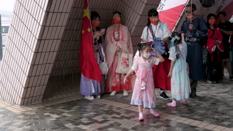 Una-Niña-Siente-La-Lluvia-Mientras-Los-Partidarios-De-China-Vestidos-Con-Trajes-De-La-Dinastía-Han-Se-Refugian-De-La-Lluvia-Durante-El-Día-Nacional-De-China.