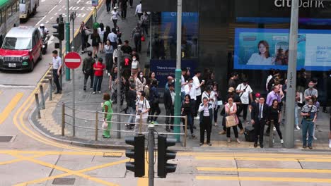 Pedestrians-wait-for-a-traffic-light-to-turn-green-at-a-crowded-zebra-crossing-junction