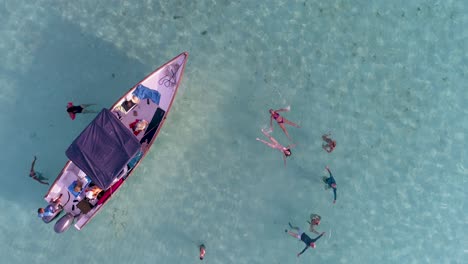 AERIAL-TOP-VIEW-SUNSET-FRIENDS-LEISURE-TIME,-People-Float-SIDE-MOTORBOAT-ENJOY-DAY-BEACH