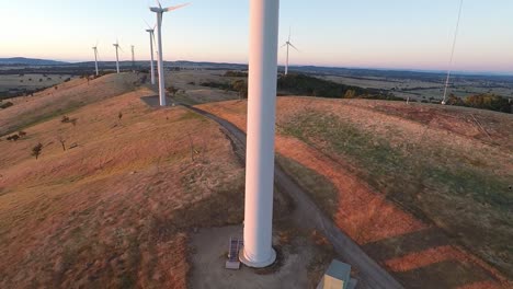 Drone-moves-up-tower-of-wind-turbine-to-reveal-the-spinning-blades-made-golden-by-the-dawn-sun