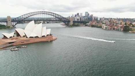 Sydney,-New-South-Wales,-Australia---24-December-2021:-Approaching-the-Sydney-Opera-House-and-Harbour-Bridge-with-boats-passing-by-in-the-harbour
