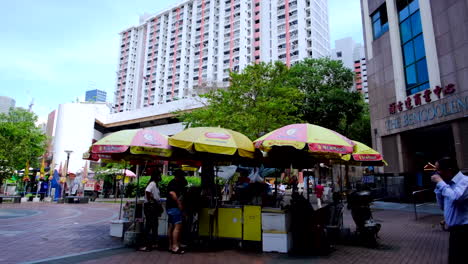 Mini-Tienda-Instalada-Solo-Con-Sombrillas-Y-Un-Mostrador-Frente-Al-Edificio-Alto-En-Singapur