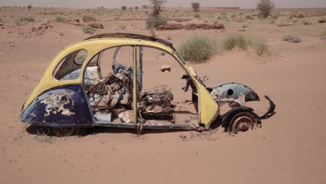 Abandoned-frame-of-old-Volkswagen-Beetle-in-Sahara-desert,-handheld-view