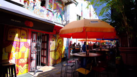 Bar-and-restaurant-set-up-with-people-drinking-alcohol-under-the-large-umbrellas-on-a-sunny-day