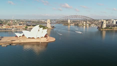 Sydney,-New-South-Wales,-Australia---25-December-2021:-Panning-past-the-Sydney-Opera-House-with-four-boats-approaching-under-the-Sydney-Harbour-Bridge