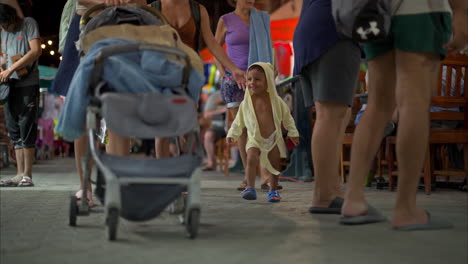 Young-hispanic-latin-baby-boy-wearing-a-bathrobe-hoodie-walking-on-the-streets-of-downtown-isla-mujeres-with-his-family-smiling-and-laughing-on-a-warm-evening