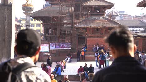 Shot-from-Behind-of-2-Nepalese-Male-friends-Speaking,-Main-Focus-on-The-Temple-On-the-Back-Kathmandu-Nepal