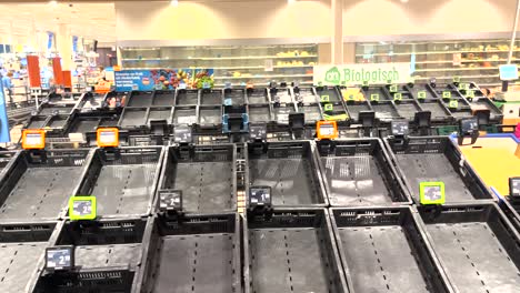 Price-tags-without-product-at-the-fruit-corner-with-empty-crates-and-shelfs-behind-in-Dutch-supermarket-during-a-distribution-center-strike