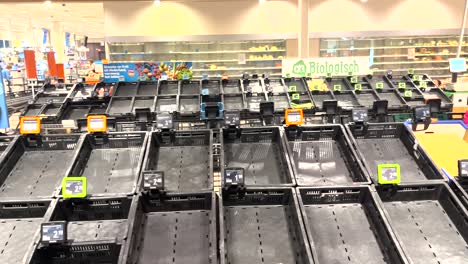 Etiquetas-De-Precios-Sin-Producto-En-La-Esquina-De-Frutas-Con-Cajas-Vacías-Y-Estantes-Detrás-En-Un-Supermercado-Holandés-Durante-Una-Huelga-En-El-Centro-De-Distribución