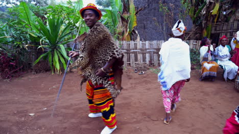 African-Ethiopian-Dorze-happy-tribal-people-with-tiger-skin-and-speer-dancing,-clapping-and-making-music-in-front-of-a-hut