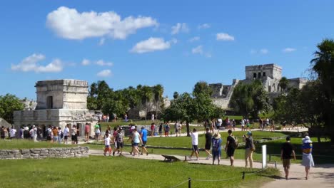 Tourists-around-Temple-of-the-Frescoes-and-The-Castle-at-Tulum-archeological-site,-Quintana-Roo,-Mexico