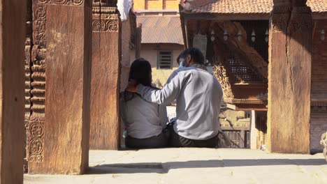 Shot-of-a-Nepalese-couple-from-Behind-seatting-on-the-side-of-a-temple,-Chatting-together-during-the-Day,-Kathmadu-Nepal