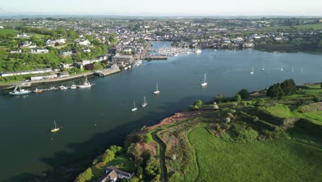 Docked-boats-on-river-curve-with-an-aerial-view-over-Kinsale-town-and-harbour-on-a-sunny-morning