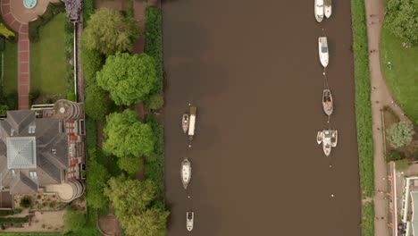Top-down-aerial-shot-over-boats-moored-to-Buoys-and-riverside-walkways