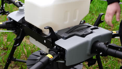 Placing-Lithium-Ion-Battery-Into-DJI-Agras-T30-Agricultural-Drone-With-Tank-For-Fertilizers-and-Seeds,-Close-Up