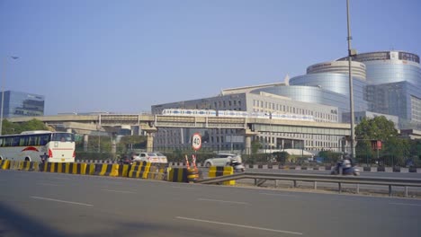 Business-center-skyline-office-buildings-of-IndusInd-bank-and-other-companies-at-DLF-cyber-city-with-the-iconic-view-of-rapid-metro-crossing-through-flyover,-Gurugram