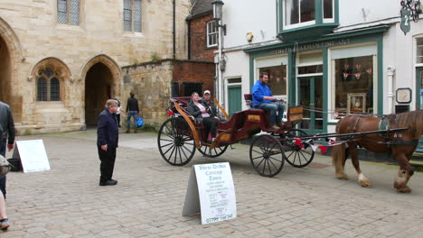 A-horse-drawn-carriage-on-an-English-cobbled-street-in-a-traditional-historic-town-called-Lincoln-in-England