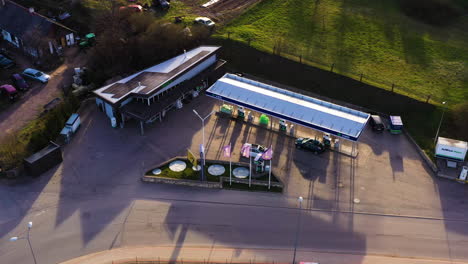 Gas-station-Virsi-A-and-the-local-car-dealership,-aerial-golden-hour-view