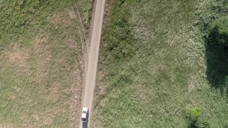 Birds-eye-view-of-car-travelling-down-dirt-road