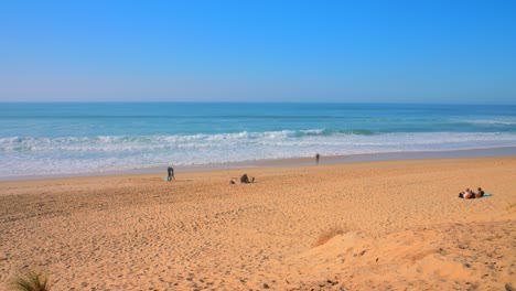 Aufnahme-Aus-Einem-Hohen-Winkel-über-Den-Sandstrand-Mit-Blick-Auf-Die-Meereswellen,-Die-An-Einem-Sonnigen-Tag-Am-Strand-Von-Les-Landes-Im-Südwesten-Frankreichs-Entlangkrachen