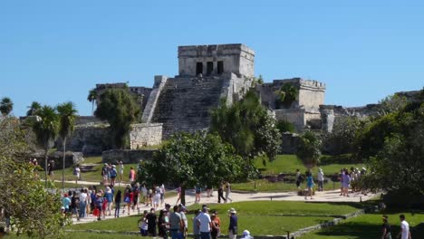 Tourists-visiting-The-Castle-mayan-ruins-at-Tulum-archeological-site,-Quintana-Roo,-Mexico