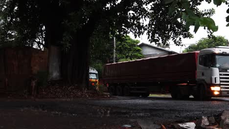 Flota-De-Camiones-Moviéndose-Uno-Tras-Otro-Sobre-Un-Gran-Agujero-En-La-Calle.