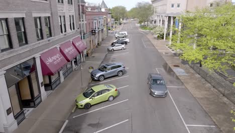 Street-in-downtown-Muncie,-Indiana-with-car-driving-and-drone-video-close-up