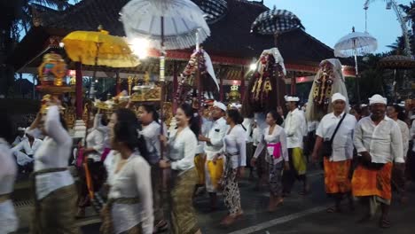 Niñas-Balinesas-Caminan-En-Procesión-En-La-Ceremonia-Del-Templo-De-Bali-Llevando-Barong-Y-Criaturas-Místicas-Como-Rangda-Y-Paraguas-Por-La-Noche.
