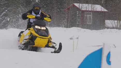 Coole-Aufnahme-Eines-Skidoo-Schneemobilrennfahrers,-Der-In-Zeitlupe-über-Einen-Hügel-In-Richtung-Kamera-Fährt,-Während-Der-Schnee-Weht