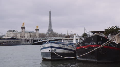 Blick-Auf-Den-Seine-Fluss-In-Der-Stadt-Paris-An-Einem-Bewölkten-Tag,-Vor-Anker-Liegende-Boote-Und-Der-Eiffelturm-Im-Hintergrund