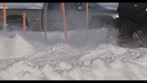 Close-up-of-skidoo-snowmobile-track-spinning-snow-at-drag-races-in-slow-motion